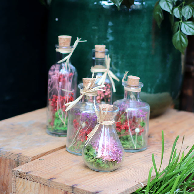 bouteille en verre foncé avec pipette sur fond floral. fleurs